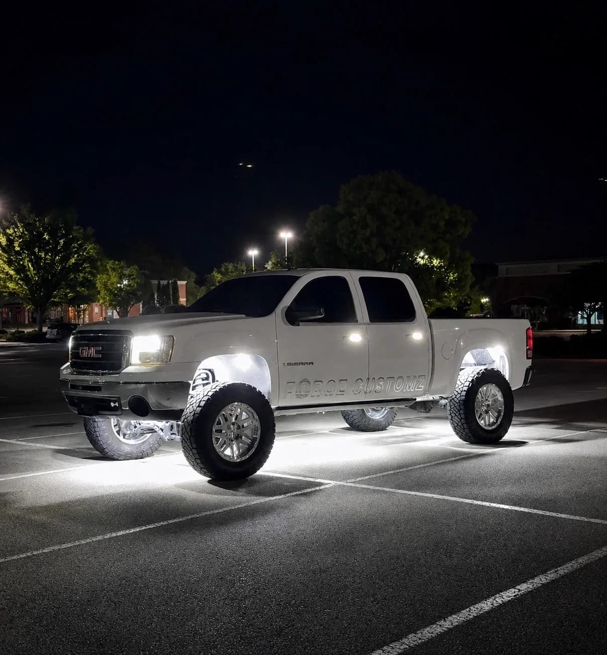 White GMC Sierra 1500 at night lit by LED rock lights and wheel lights